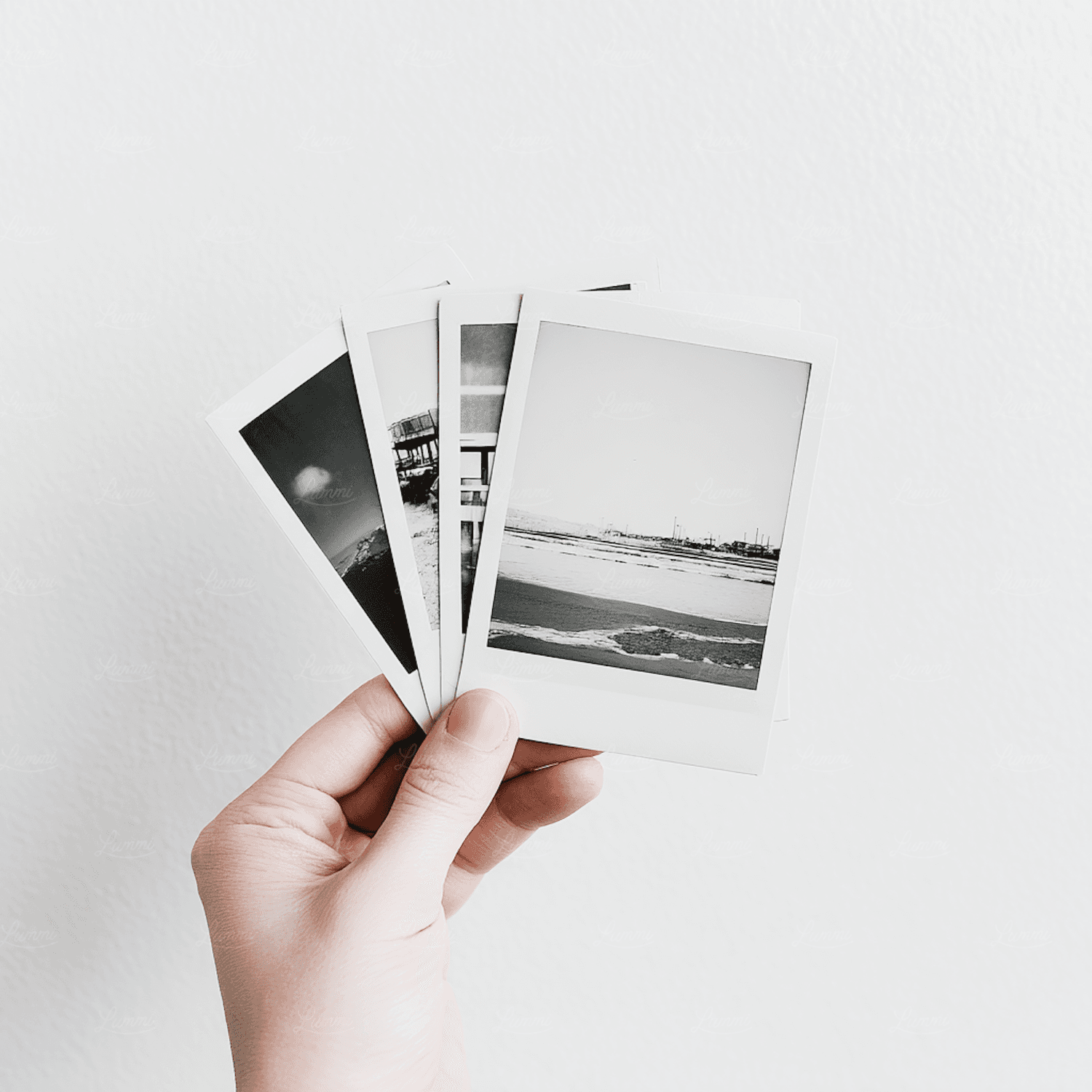 A set of small black and white prints held up against a white wall